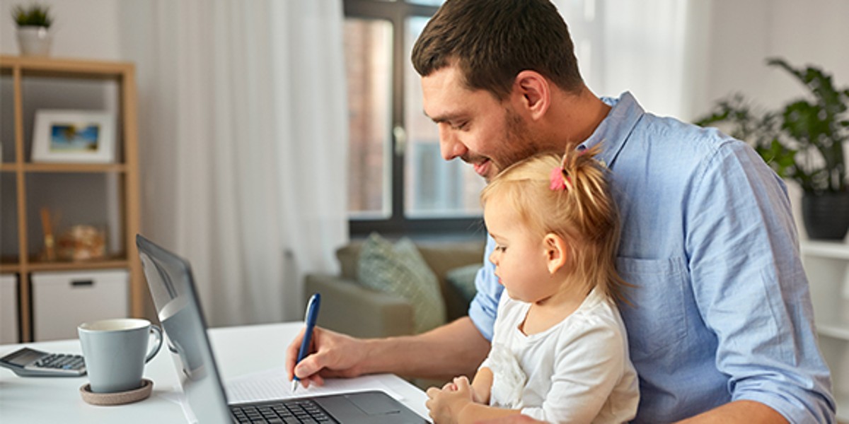 Mann sitzt mit Kind am Laptop und macht Home-Office