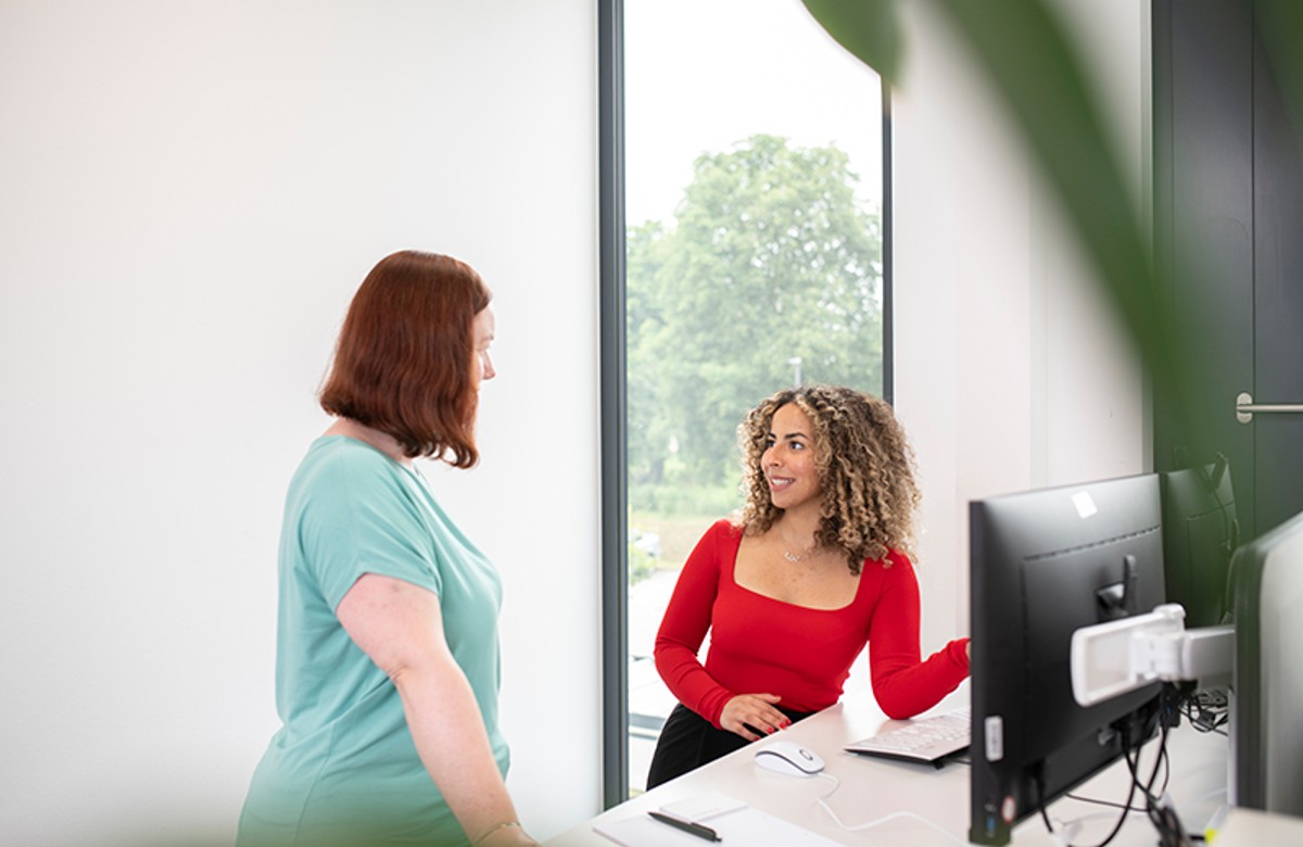 Zwei Personen im Gespräch vor PC