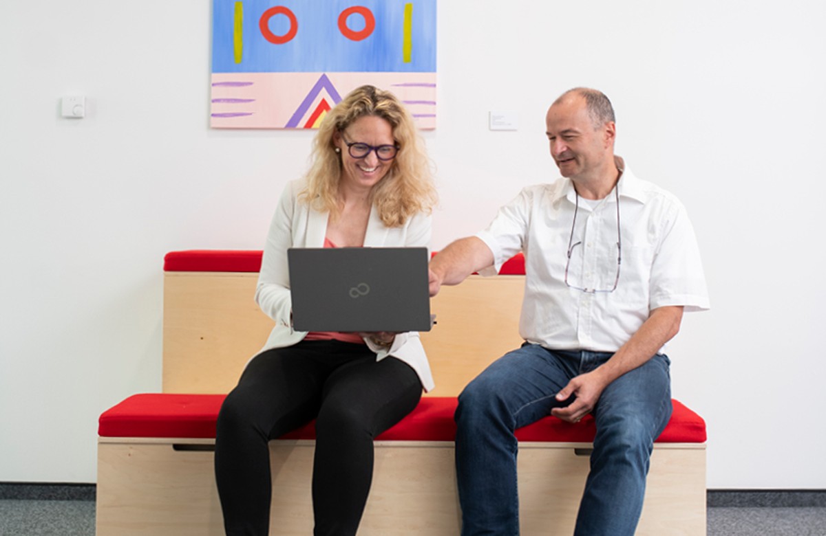 Zwei Personen im Gespräch mit Laptop Zwei Personen im Gespräch mit Laptop